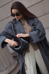 a lady in a brown top, a grey long wool coat and a pair of white pants